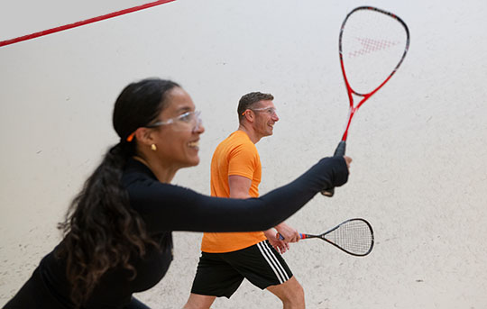 A woman and man playing squash on court