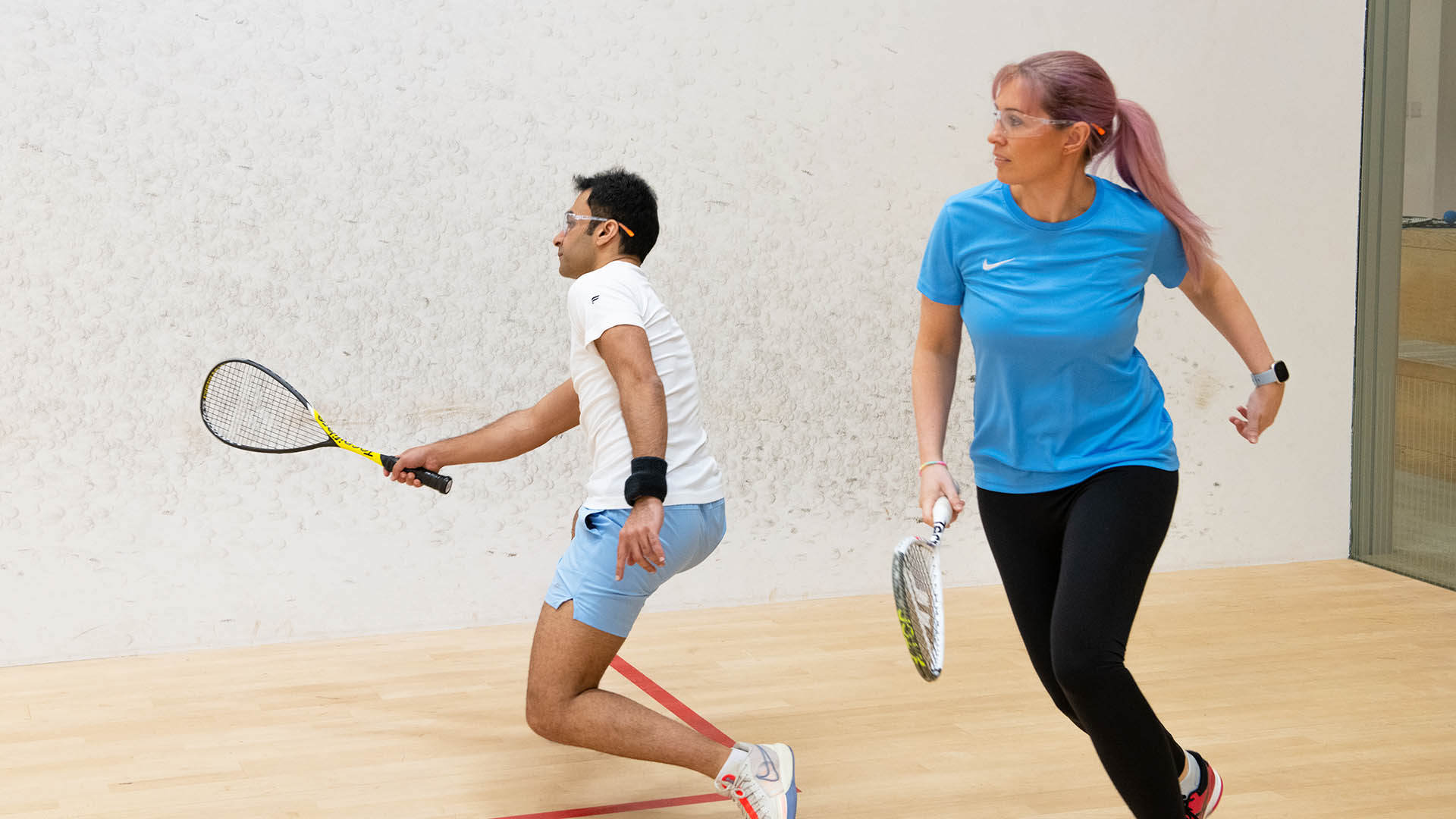 A man and a woman playing squash together
