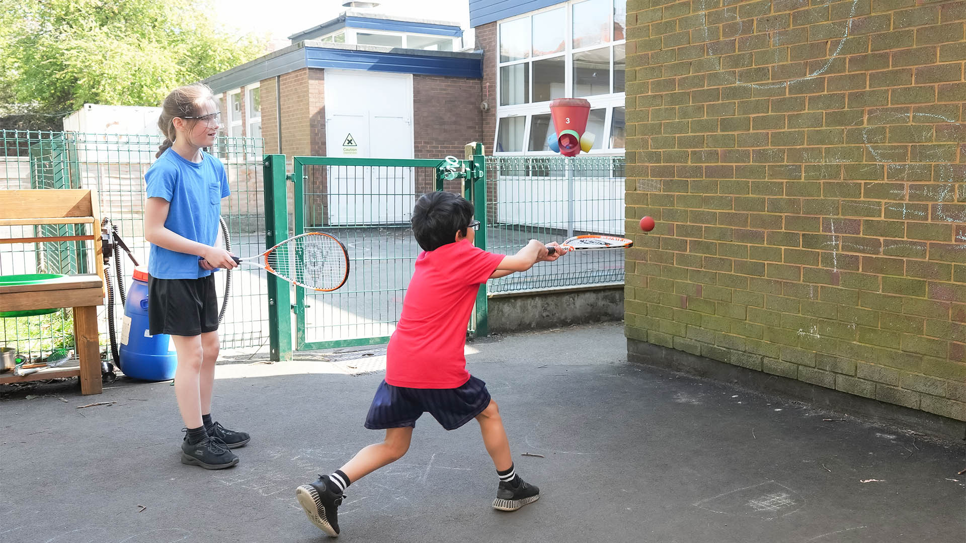 Children playing squash on an outdoor playground wall