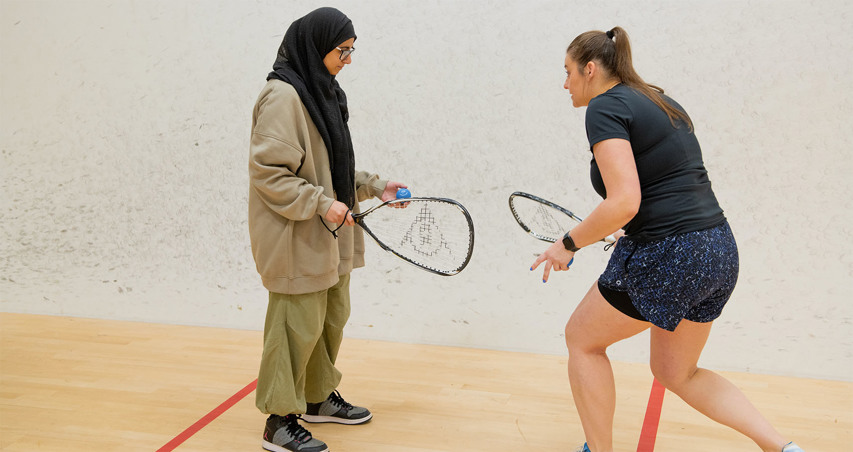 A squash coach leading a female player