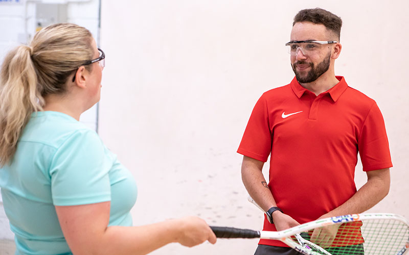 A woman and a man on a squash court talking