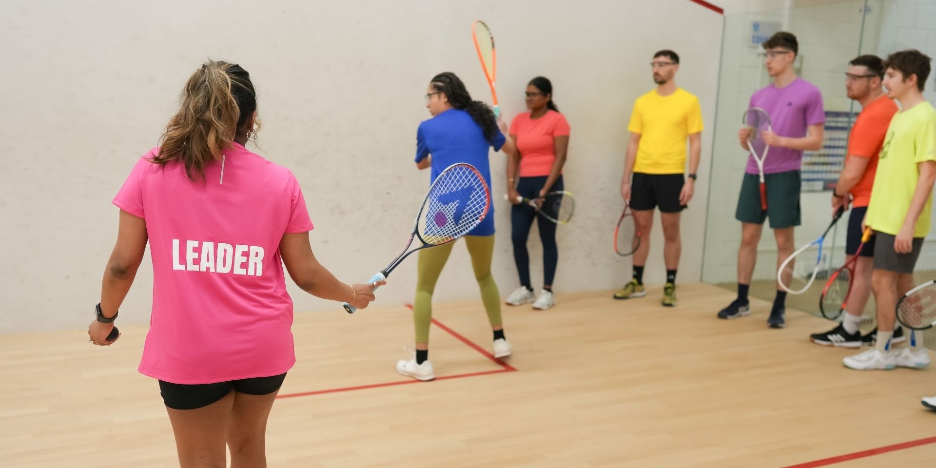 A group of men and women playing squash
