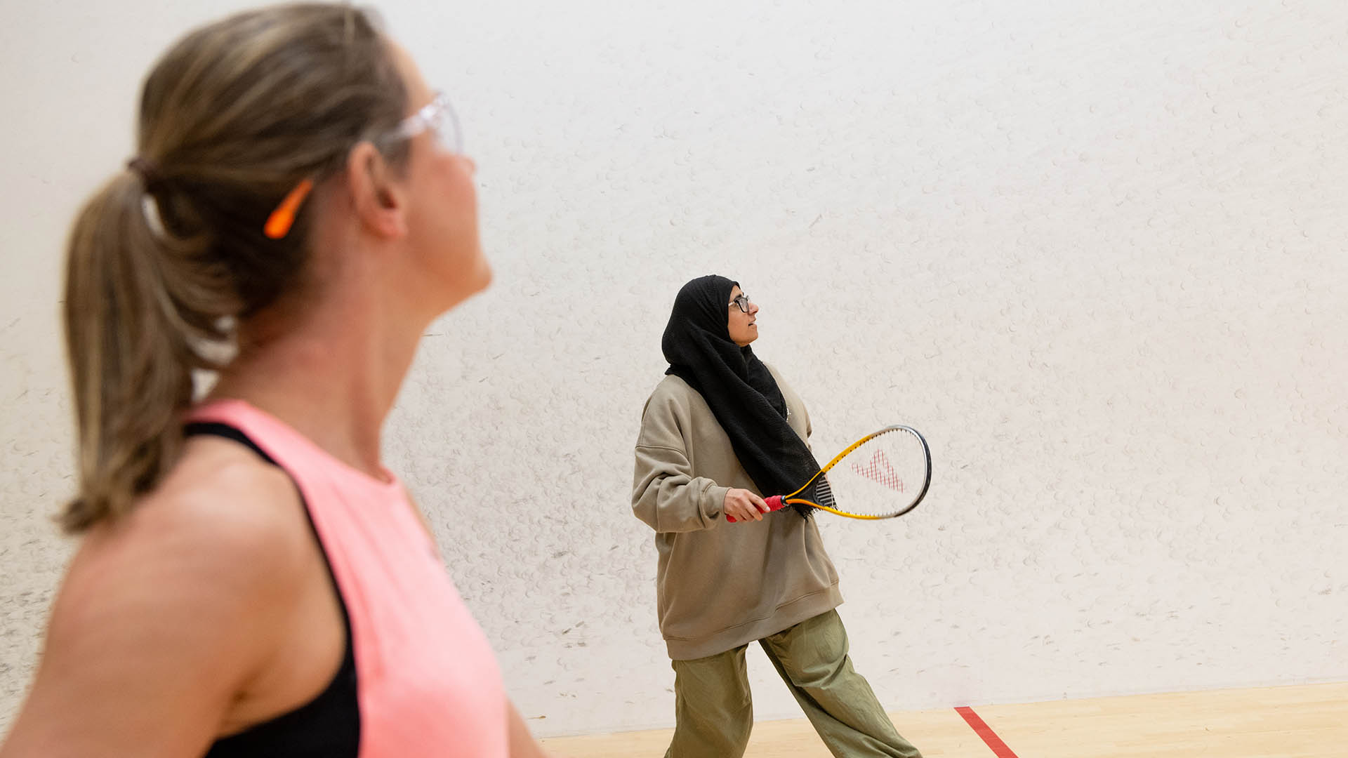 Two women playing squash together