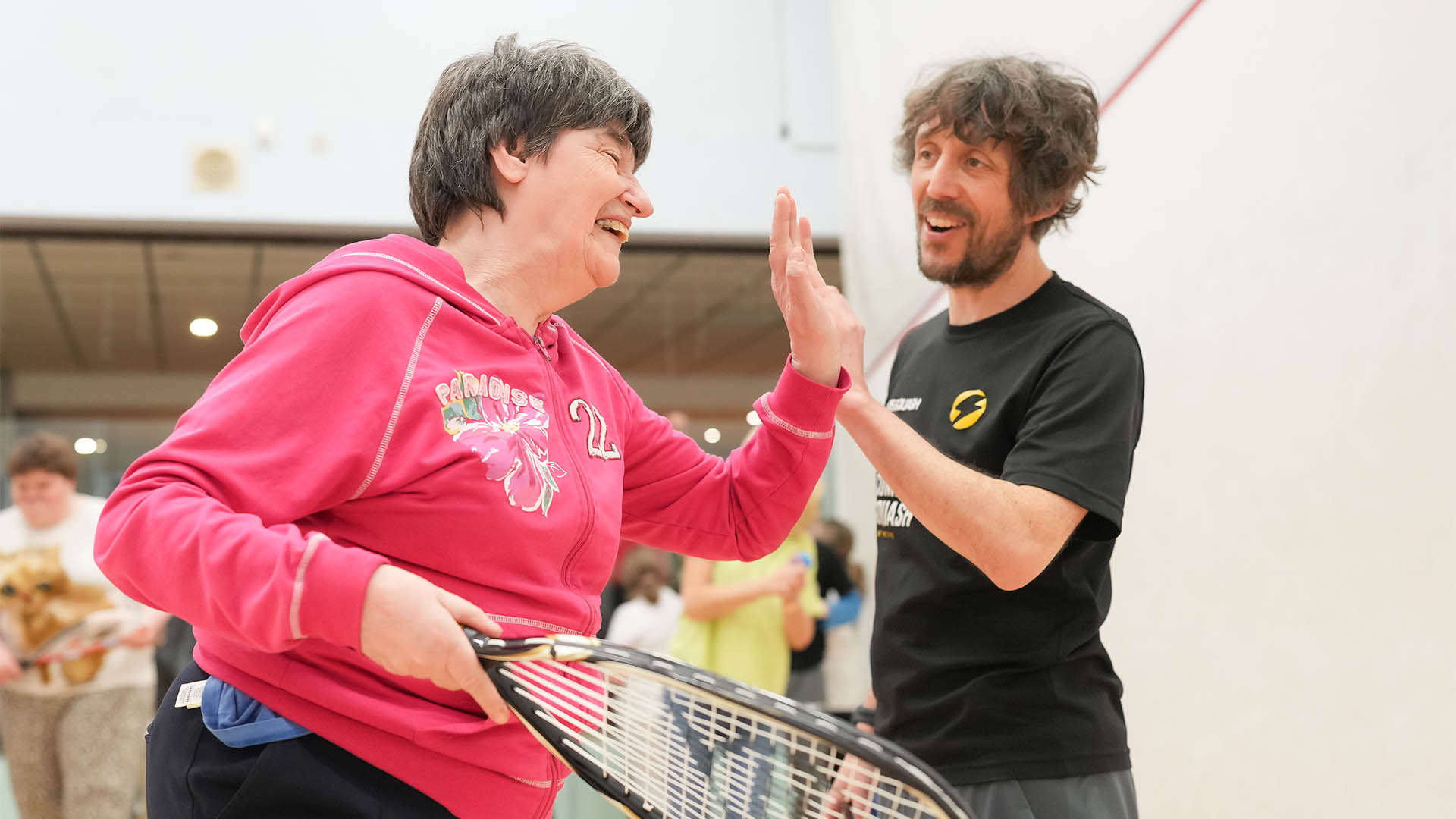A squash coach supporting a female player on court