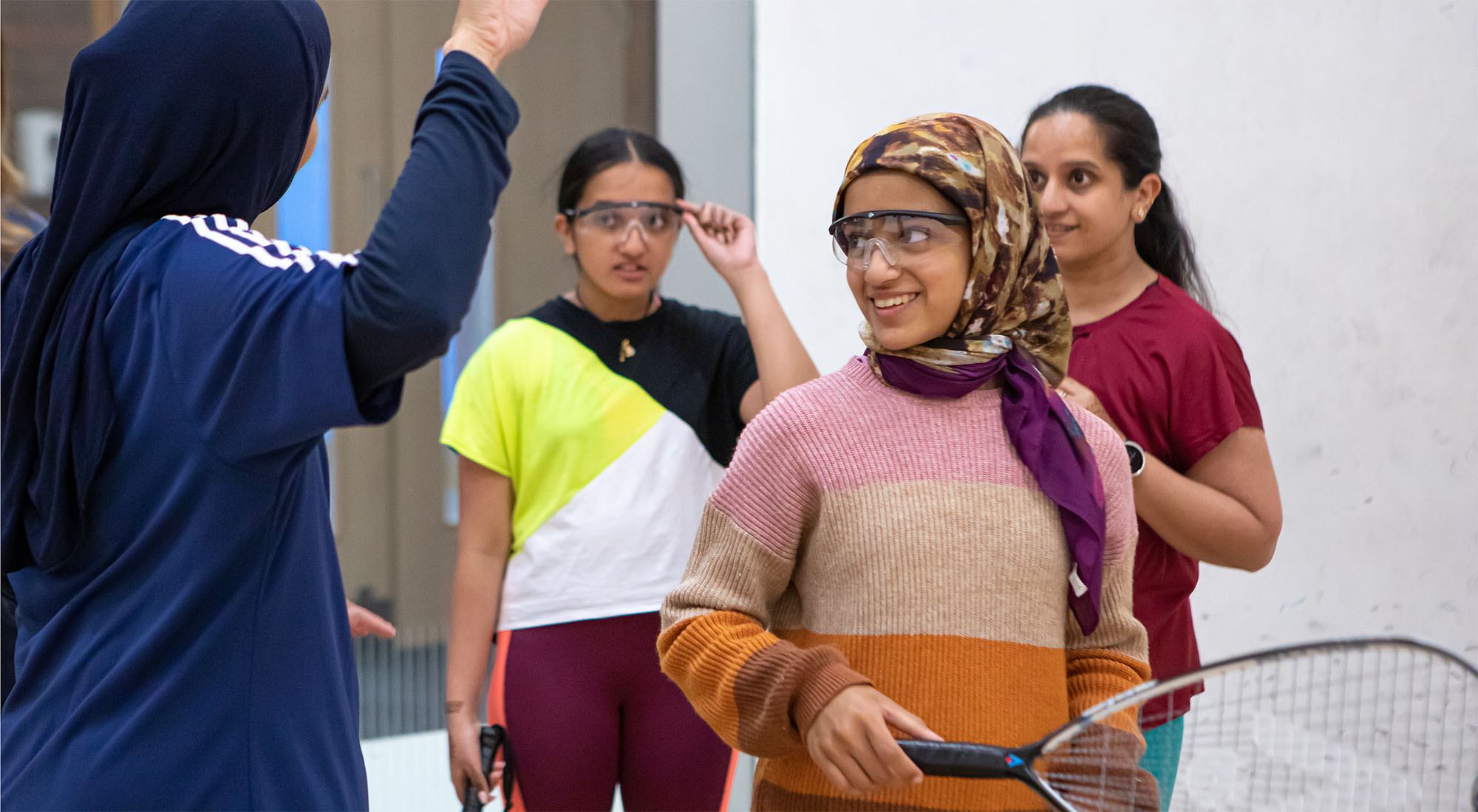 A Muslim coach instructing women on a squash court