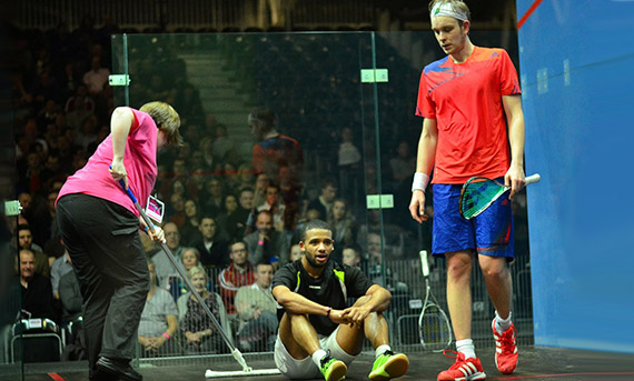 A volunteer sweeping the court during a James Willstrop match