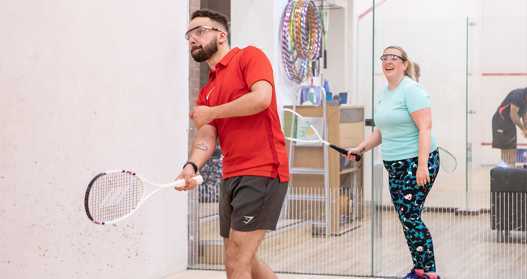 A male and female player playing squash on court