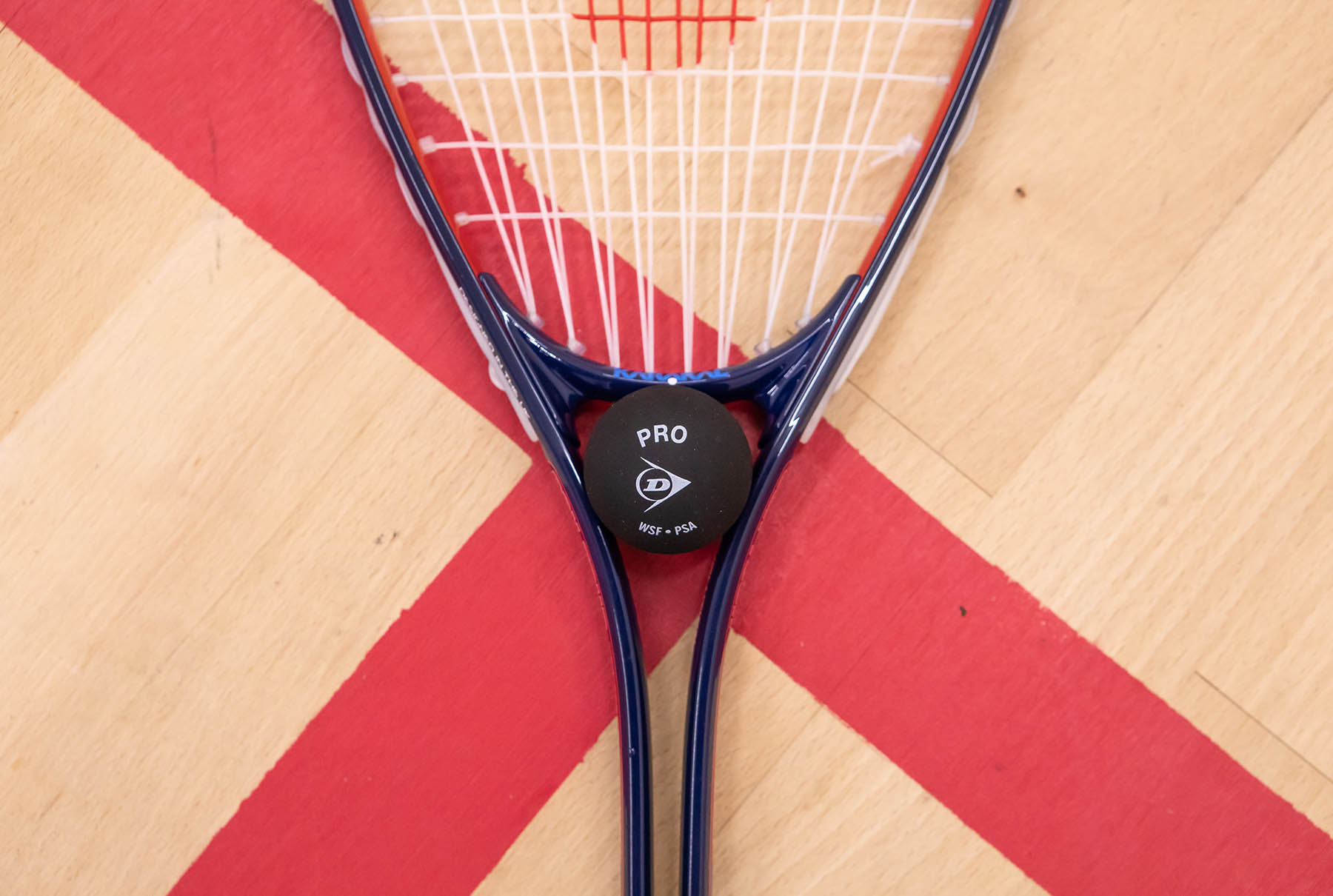 A squash racket with a ball on a squash court